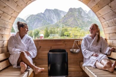Gjester sitter i badstue med utsikt mot fjell, Nyvågar Lofoten